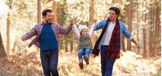 couple with daughter walking through fall woodland